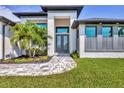 Close up of front entrance featuring large double-door entry, gray brick walkway, and minimalist landscaping at 8634 Santa Cruz Dr, Port Charlotte, FL 33981
