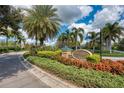 Beautiful Pennington Place community entrance with mature landscaping and blooming flower beds at 9118 Coachman Dr, Venice, FL 34293