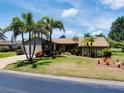 Inviting home with a lush green lawn, mature palm trees, and a well-maintained two-car garage at 915 S Doral Ln, Venice, FL 34293
