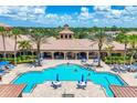 Overhead view of sunny community pool and sun deck with tables, chairs, and umbrellas, flanked by palm trees at 11103 Batello Dr, Venice, FL 34292