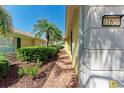 The side of the home shows lush tropical landscaping, brick paver walkway and yellow siding at 11624 Garessio Ln, Sarasota, FL 34238
