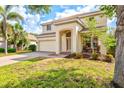 Two-story home featuring a two-car garage, a welcoming front porch with furniture and a well-manicured lawn with beautiful landscaping at 11986 Granite Woods Loop, Venice, FL 34292