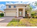 Two-story home featuring a two-car garage, a welcoming front porch, and a well-manicured lawn with beautiful landscaping at 11986 Granite Woods Loop, Venice, FL 34292