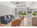 Bright living room featuring tray ceilings, ceiling fan, and access to the outdoor patio at 1228 Pineland Ave, Venice, FL 34285
