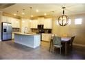 Spacious kitchen featuring granite counters, stainless appliances, white cabinetry, and a breakfast table with stylish chandelier at 136 Positano Trl, Nokomis, FL 34275
