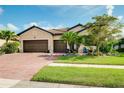 Charming single-story home boasts a three-car garage, tiled roof, brick driveway, and lush landscaping at 13634 Vancanza Dr, Venice, FL 34293
