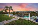 Beautiful backyard with a private dock, swing, and waterway view at sunset, surrounded by lush landscaping at 14398 Fort Worth Cir, Port Charlotte, FL 33981