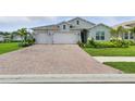 Charming single-Gathering home featuring a brick driveway, a two-car garage, and a well-manicured lawn with mature landscaping at 15963 Crofton Springs Way, Port Charlotte, FL 33953