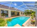 Screened-in pool with a tiled deck and tropical landscaping at 188 Grand Oak Cir, Venice, FL 34292
