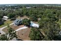 Wide aerial shot showcases the home's layout, neighboring houses, and lush wooded surroundings in the distance at 2008 55Th E Ave, Bradenton, FL 34203