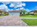 Lovely one-story home with three-car garage, a brick driveway, manicured lawn, and attractive landscaping at 20235 Granlago Dr, Venice, FL 34293