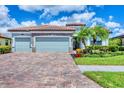 A beautifully landscaped one-story home boasting a brick driveway, stone accents, and a three-car garage at 20235 Granlago Dr, Venice, FL 34293