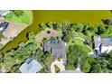 Aerial view of a home with a swimming pool surrounded by green trees, grass, and a lake at 249 Hallcrest Ter, Port Charlotte, FL 33954