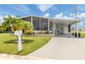 Inviting single-story home with a well-manicured lawn, covered parking, and a screened-in porch area at 349 Mariner Dr, North Port, FL 34287
