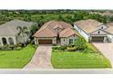 Aerial view of a home with a brick driveway, well-manicured lawn, and lush landscaping at 4740 Royal Dornoch Cir, Bradenton, FL 34211