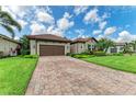 Paver driveway leading to a home with lush landscaping and a brown two-car garage at 4740 Royal Dornoch Cir, Bradenton, FL 34211