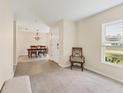 Open-concept living room featuring neutral carpet, tile entryway, and dining area with chandelier at 4890 Laramie Cir, North Port, FL 34286