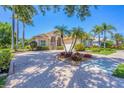 Beautifully landscaped front yard with palm trees and a brick driveway enhance curb appeal at 5018 Bella Terra Dr, Venice, FL 34293
