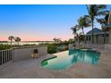 Stunning infinity pool offers panoramic waterfront views, set against a backdrop of lush palm trees at 755 Eagle Point Dr, Venice, FL 34285