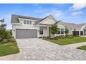 Charming two-story home with a gray garage door, complemented by stylish landscaping and a patterned driveway at 18136 Foxtail Loop, Venice, FL 34293