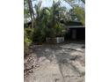 Exterior shot of a home with overgrown tropical foliage and gravel drive at 202 Bayview Pkwy, Nokomis, FL 34275