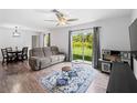 Bright living room featuring a sliding glass door, ceiling fan, and open layout with wood-look floors at 2355 Allsup Ter, North Port, FL 34286