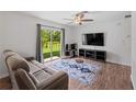 Cozy living room with a sliding glass door, ceiling fan, and modern decor on wood-look floors at 2355 Allsup Ter, North Port, FL 34286