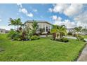 Well-maintained front yard showcases colorful landscaping, a green lawn, and mature palm trees at 239 Cutter Ct, North Port, FL 34287