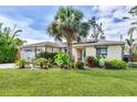 Charming one-story home with a lush green lawn and mature landscaping, including a beautiful palm tree at 2445 Apache St, Sarasota, FL 34231