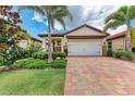 Attractive home featuring a tile roof, two-car garage, and brick paved driveway with tropical landscaping at 257 Teramo Way, Nokomis, FL 34275