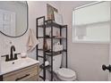 Well-lit half bathroom featuring a modern vanity, toilet, and decorative shelving for storage at 3340 Webber St, Sarasota, FL 34239