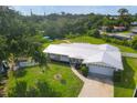 Charming home with a new white metal roof, lush green lawn, mature trees, and pristine landscaping at 458 Ceil Ct, Nokomis, FL 34275