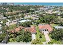 Aerial view of a home highlighting the tile roof, driveway, and surrounding lush greenery near the ocean at 609 Madrid Ave, Venice, FL 34285