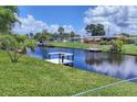 Canal view with lush green grass and private docks for boating and relaxation on a sunny, cloud filled day at 6821 Marius Rd, North Port, FL 34287