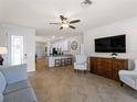Open-concept living room featuring tile flooring, a ceiling fan, and a view into the kitchen at 9917 Haze Dr, Venice, FL 34292