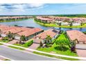 Stunning aerial view of homes on a lake in a gated community with lush landscaping and terra cotta tile roofs at 10061 Cozy Grove Dr, Venice, FL 34293