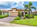 Inviting home with a red tile roof, well-manicured landscaping, and a paver driveway leading to the garage at 10061 Cozy Grove Dr, Venice, FL 34293