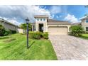 Attractive home showcasing a manicured lawn, lush shrubbery, and a brick-paved driveway at 11240 Spring Gate Trl, Bradenton, FL 34211