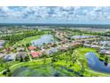 Expansive aerial shot of a community featuring shimmering lakes and verdant golf courses under a bright sky at 1210 Eagles Flight Way, North Port, FL 34287
