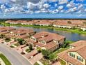 Aerial scene capturing a lakefront community featuring tan townhomes with red tile roofs at 12590 Ghiberti Cir # 201, Venice, FL 34293