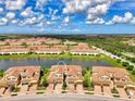 Panoramic aerial shot of tan townhomes with red tile roofs surrounding a picturesque lake at 12590 Ghiberti Cir # 201, Venice, FL 34293