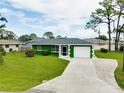 Inviting single-story home with a well-maintained lawn, a driveway and a charming green exterior at 1536 Porpoise Rd, Venice, FL 34293