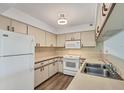 Efficient kitchen design with white appliances, wood-look flooring, and ample cabinet storage space at 1614 Quail Lake Dr, Venice, FL 34293