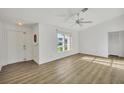 Bright living room featuring wood-look flooring, a ceiling fan, a front door, and a large window at 1614 Quail Lake Dr, Venice, FL 34293