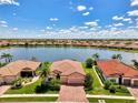 Beautiful aerial view of a lakeside home with a brick driveway, manicured lawn, and a tranquil lake view at 20370 Grazie Pl, Venice, FL 34293