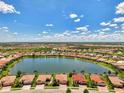 Expansive aerial view showcasing community homes surrounding a large lake on a sunny day with fluffy clouds at 20370 Grazie Pl, Venice, FL 34293