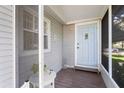 Inviting enclosed front porch featuring a pastel blue door, wood floors and white trim at 2185 Park Rd, Venice, FL 34293