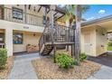 Exterior view of condo with covered staircase, front storage, and small garden on sunny day at 330 Mission N Trl # B, Venice, FL 34285