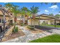 Condo exterior featuring covered parking, walkways with mature trees, and maintained landscaping on a sunny day at 330 Mission N Trl # B, Venice, FL 34285