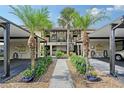 Charming condo exterior with tropical landscaping, palm trees and convenient covered parking at 330 Mission N Trl # F, Venice, FL 34285